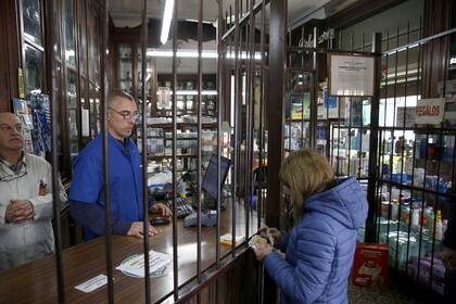 En la histórica farmacia de Horacio Torina (izquierda), las rejas separan el mostrador del público
