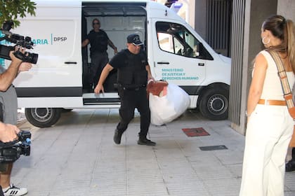En la imagen, se ve a la policía bajando todas sus pertenencias en bolsas blancas