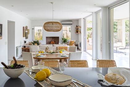 En la isla, taburetes ‘Awen’ (Lacroze Studio). Comedor: lámpara de techo (Compañía Nativa), mesa ‘Kala’ de petiribí y sillas ‘Maki’ tapizadas en lino antimanchas (todo de Lacroze Studio), individuales de papel (Maison de Papier), camino de gasa (Natural CS).