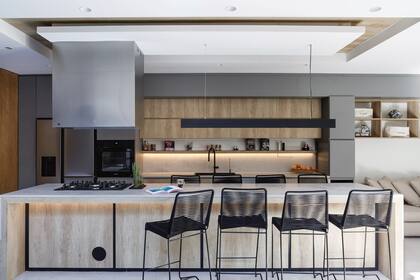 En la isla y el cielo raso, revestimiento ‘Nebraska’ (Egger); en las alacenas grises, melamina ‘Seda Notte’ (Faplac). Mesada de Purastone ‘Concrete’. Lámpara colgante (Siluz). Bacha y grifería (Mi Pileta). Artefactos (Samsung).