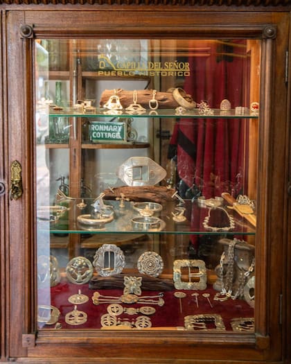 En la vitrina, rastras de alpaca y cuero, con monedas y piezas talladas a mano por Arredes, mates y bombillas.