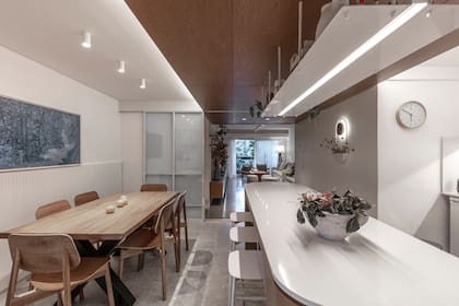 En la zona del comedor se conservó la mesa que tenían los dueños y se acompañó con sillas en petiribí (Estudio.te). Trío de plafones cilíndricos (Iluminación Agüero)