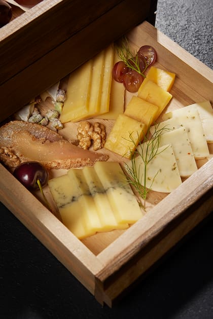 En las tablas de quesos hay variedades como queso brie, musters, mimolette y gascogne junto a almendras, uvas, dátiles, tomates secos y gremolata de peras, además de miel especiada.