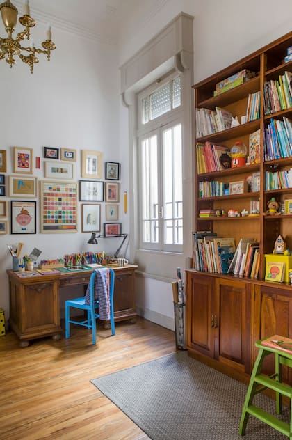 En los estantes, libros con cajas de música de colección, clásicos de María Elena Walsh, juguetes de madera (La Maravillosa Calle Bolton) y varios Playmobil. La alfombra al pie de la biblioteca delimita el área de juego y lectura.