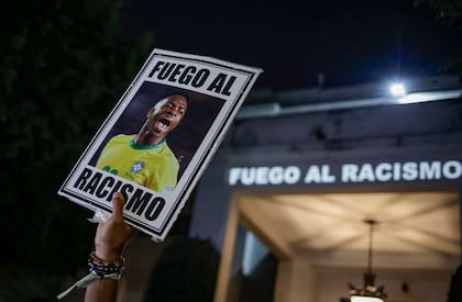 En mayo de 2023, un manifestante sostiene una imagen de Vinícius con un mensaje en portugués: "Pelea contra el racismo"; el brasileño, víctima de burlas de hinchas rivales, fue un adalid de esa causa en el fútbol español.