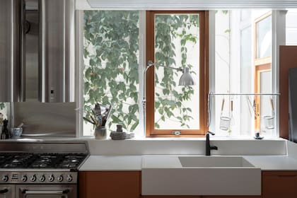 En medio del muro cortina, así como en los bajomesadas y revestimientos, aparece
un guiño a la madera, que dialoga con la historia material de la casa.