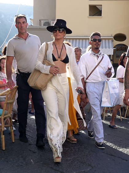  En otro de sus looks de playa, Jennifer López mostró un poco de escote sin dejar de priorizar la elegancia y el estilo para salir de compras por la ciudad de Capri seguida por su séquito