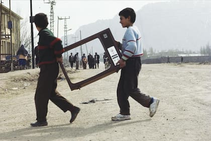 En pantalla. Dos niños kurdos cruzan la calle cargando restos de un televisor (1993)