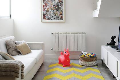 En paralelo al living, del otro lado de la escalera, el playroom con alfombra tejida en telar (Elementos Argentinos) y un mueble laqueado diseñado por Ariel y Romina.