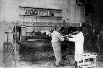 En plena tarea, dos herreros colocan una herradura al caballo que está recostado en la camilla. La caballeriza estaba equipada para el cuidado de los equinos