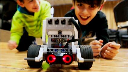 En primer plano, el robotito terminado; atrás, orgullosos, dos de sus creadores