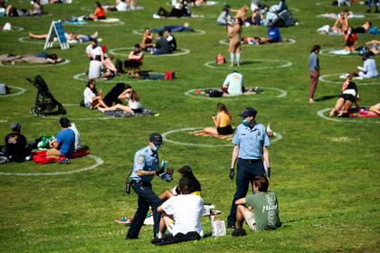 Cadetes de la policía ofrecen barbijos a los visitantes del Dolores Park, en San Francisco