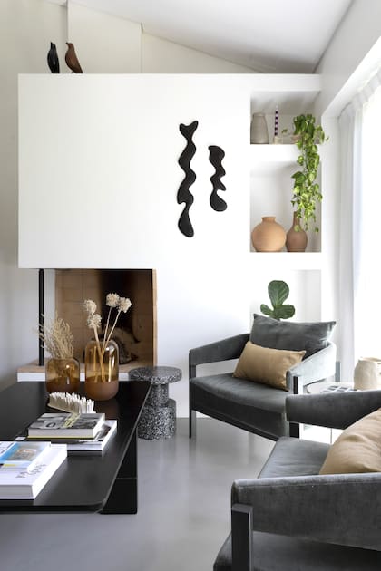 En su casa, Sara cerró el frente de la chimenea para colgar la obra en kiri de Agustín Leiro y crear nichos para objetos decorativos