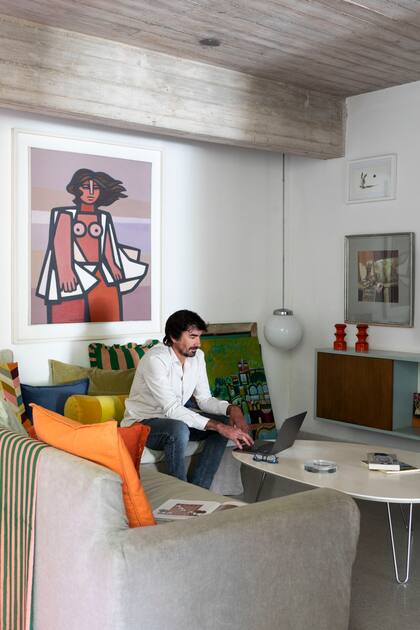 En toda la casa, obras de la colección de Espacio Pinasco, la galería que dirige Santiago, el marido de Cecilia, sentado en el living. Lámpara esférica (Red Sur). Almohadones (Lote Propio).
