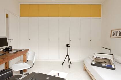 En un dormitorio donde impera el blanco se eligió un amarillo intenso para cubrir las puertas superiores del placard. Es un recurso sencillo que potencia la decoración del espacio