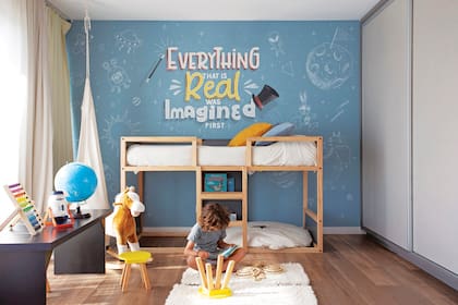 En un extremo, la cama Montessori de Gino (Deco Lodd), con puf (BF Deco Kids). Mural (Pomeloh Amarillo). En el centro comparten un espacio de juego.