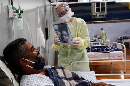 En un hospital de San Pablo, un paciente con Covid-19 habla con su esposa y su hijo por videollamada