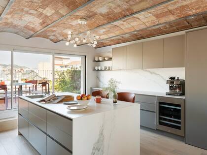 En un lindisimo contraste de texturas y tiempos, lámpara 'Birdie', del diseñador alemán Ingo Maurer, colgando del techo de bovedilla. Isla de Corian con cajones olleros.