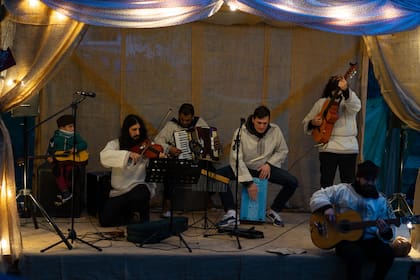 En un pequeño escenario, una banda de músicos toca y canta en ruso