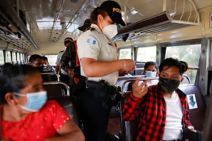En un puesto de control en Pajapita, Guatemala, un policía revisa la documentación de los pasajeros para verificar si hay migrantes provenientes de la caravana de centroamericanos, para evitar que continúen su viaje hacia Estados Unidos