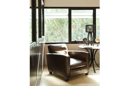 En un rincón junto a la ventana, un pequeño living compuesto por un antiguo sillón de cuero, y una mesita con estructura de hierro y tapa en madera, generan una atmósfera especial en esta oficina