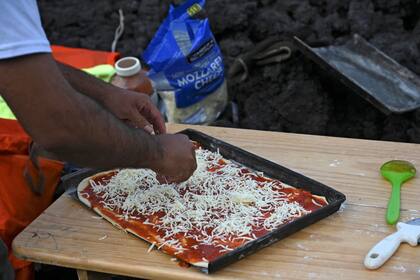En una cocina improvisada entre filosas rocas volcánicas, David García extiende la masa y coloca los ingredientes para formar la pizza
