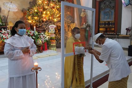 Un plástico protector separa al cura de los fiéles en una misa navideña en Bali, Indonesia