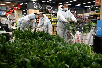 En una imagen proporcionada por la agencia de noticias Xinhua, trabajadores preparan bolsas de artículos comestibles que serán entregadas a los residentes que se encuentran en confinamiento en Xi'an, un poblado del noroeste de China (Liu Xiao/Xinhua vía AP)