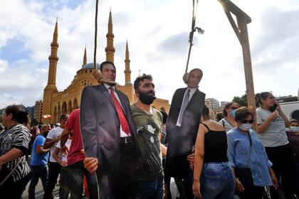 En una protesta en Beirut un hombre posa con una foto del primer ministro libanés, Hassan Diab (izq.), Y el presidente ejecutivo de las Fuerzas Libanesas, Samir Geagea, que aparecen colgados