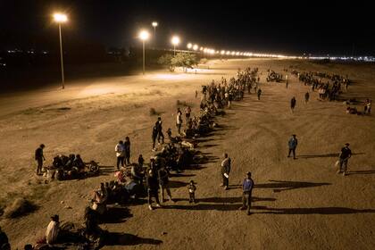 En una vista aérea, los inmigrantes esperan cerca de la valla fronteriza entre Estados Unidos y México, con la esperanza de que los agentes fronterizos de Estados Unidos procesen su asilo el 8 de mayo de 2023 en El Paso, Texas