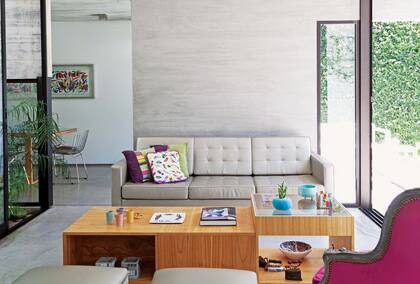 Engamado con el sofá Manifesto), el muro sin decoración pone el foco en la nobleza del material. El sillón de estilo retapizado en pana fucsia quiebra la monocromía.