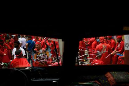 Enmarcados por el parabrisas de un autobús, los bailarines del diablo se reúnen durante las celebraciones del Corpus Christi en San Francisco de Yare, Venezuela, el jueves 3 de junio de 2021, en medio de la pandemia de coronavirus