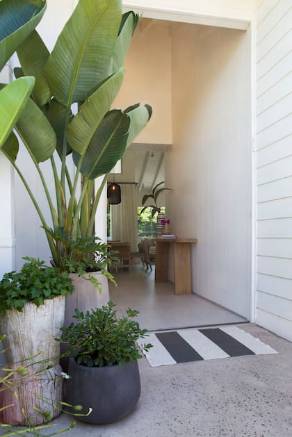 Entrada con macetas de Coin Vert. Más allá de la consola se divisa el living-comedor con ventanas al jardín.