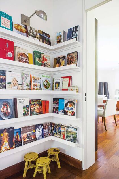 Entre el comedor, la cocina y el family, el tesoro de la casa familiar: una biblioteca diseñada con poca profundidad para exhibir las tapas de sus libros de cocina preferidos.