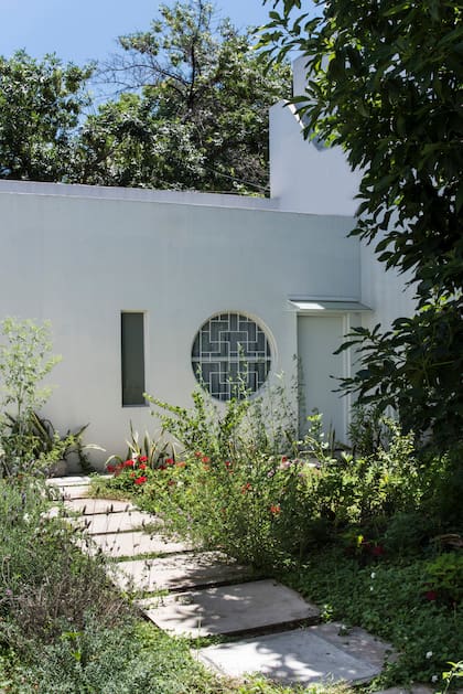Entre el cuarto de huéspedes que da a la calle (arriba) y la casa principal, un jardín que diseñó el paisajista Ignacio Montes de Oca con un camino central de baldosones.