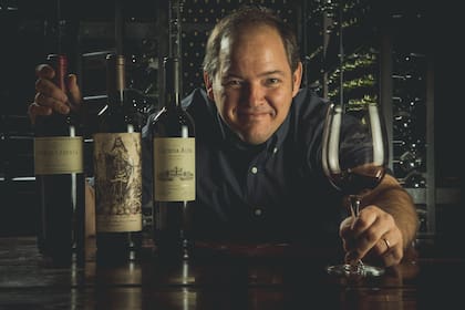 Ernesto "Nesti" Bajda, con tres de sus vinos; en el medio, el Malbec Argentino premiado