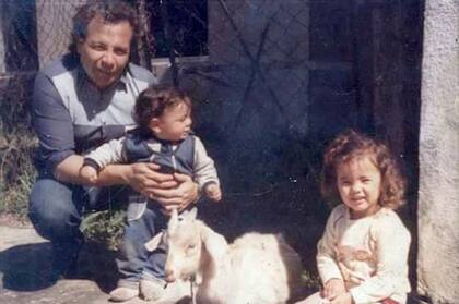 La autora mira la cámara. Su papá sostiene a su hermano.