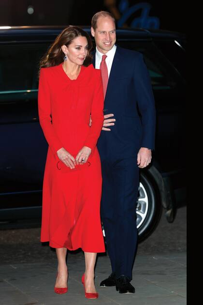 Escoltada por el príncipe William, Kate llega a la abadía de Westminster con un look total red: tapado con lazo al cuello de Catherine Walker, stilletos de Gianvito Rossi, sobre de Miu Miu y los impresionantes pendientes de zafiro y diamantes que pertenecieron a la madre de la reina Isabel II.
