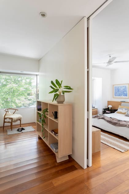 Escondida, la puerta corrediza se pierde en el interior del muro y no hay guía inferior que interrumpa la continuidad del entablonado. Alfombra (Seara).