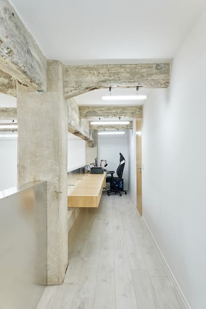 Escritorio flotante y puerta enchapados en guatambú (Wollstudio). Para iluminar, tubos (Huup) sujetados a las vigas.