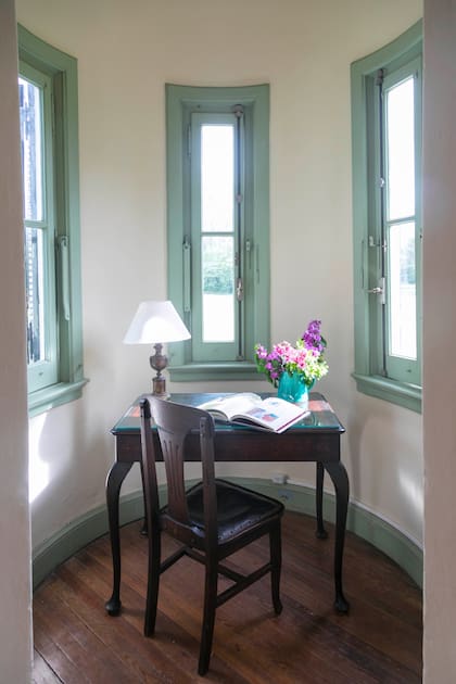 Escritorio rodeado de ventanas en la habitación “La Torre”, refugio ideal para poetas y soñadores.