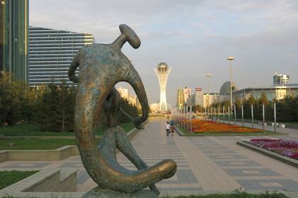 Escultura en el boulevar de Baiterek, con la torre al fondo y hacia la derecha el edificio con forma de huevo que alberga el Archivo General.
