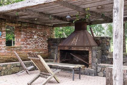 Espacio diseñado por Carlos Thays, donde una antigua construcción fue aprovechada para unirle una pérgola de madera. Debajo, la chimenea realizada en piedra laja y hierro con remaches, hace las veces también de parrilla.