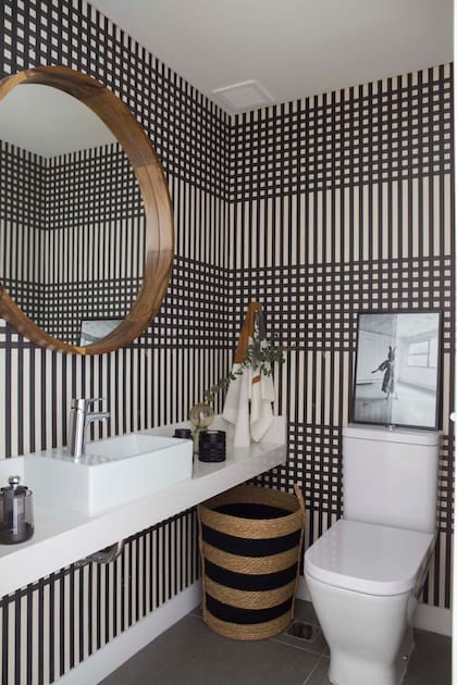 Espejo circular con marco de petiribí (Moscú Company). Empapelado (Enamorada del Muro). En el cesto de fibras naturales se reúnen con gracia los colores y motivos de ambos.