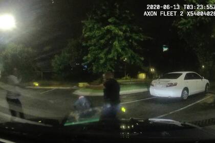 Esta captura de pantalla tomada del video de la cámara del tablero de instrumentos proporcionado por el Departamento de Policía de Atlanta muestra a Rayshard Brooks, a la izquierda, y al oficial Garrett Rolfe apuntando a Tasers el uno al otro, mientras que el oficial Devin Brosnan se levanta después