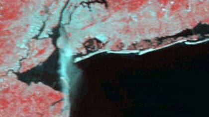 Esta foto fue tomada por el espectrorradiómetro de imágenes de baja resolución MODIS, pocas horas después del ataque. Los píxeles rojos de la foto muestran la vegetación y las manchas azules claras el concreto. Se ve además el humo de las torres destruidas fluir hacia la costa de Nueva Jersey.