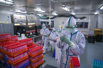 Esta foto tomada el 23 de noviembre de 2020 muestra a técnicos procesando pruebas de coronavirus Covid-19 en un laboratorio en Tianjin, China