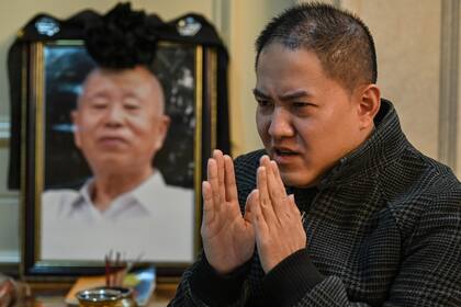 Esta foto tomada el 24 de noviembre de 2020 muestra a Liu Peien junto a un retrato de su padre, quien murió después de tener síntomas de Covid-19, en Wuhan, provincia central de Hubei en China