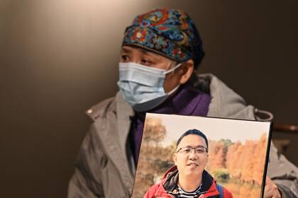 Esta foto tomada el 25 de noviembre de 2020 muestra a Zhong Hanneng hablando durante una entrevista con AFP junto a un retrato de su hijo que murió de Covid-19 en Wuhan, en la provincia central de Hubei en China