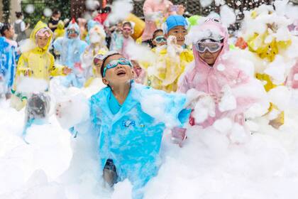 Esta foto tomada el 31 de mayo de 2023 muestra a niños jugando con espuma en un jardín de infantes durante un evento para celebrar el Día Internacional del Niño en Nanjing, en la provincia oriental china de Jiangsu